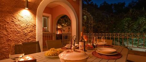 Un espace de restauration en plein air avec une table dressée pour un repas, entouré d’un mur en pierre et d’une balustrade.