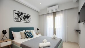 A modern hotel room with a bed, a world map artwork, an air conditioning unit, and a television. - Mylos 4 apt, Apartment (Agios Nikolaos)
