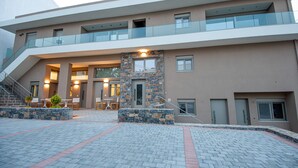A multi-story building with a modern design, featuring a central staircase, outdoor seating area, and a stone accent wall. - Mylos 4 apt, Apartment (Agios Nikolaos)
