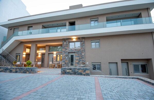 A multi-story building with a modern design, featuring a central staircase, outdoor seating area, and a stone accent wall.