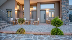 A modern building with a covered outdoor seating area, stone steps, and a staircase. - Mylos 4 apt, Apartment (Agios Nikolaos)