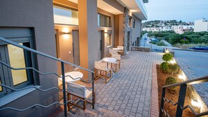 An outdoor seating area with tables and chairs, a stone wall, and a view of a residential area. - Mylos 4 apt, Apartment (Agios Nikolaos)