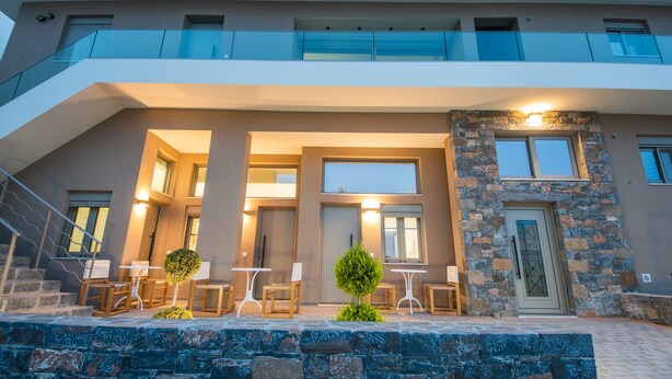 A modern building with a balcony, outdoor seating area, and a stone facade. - Mylos 4 apt, Apartment (Agios Nikolaos)