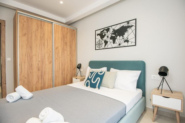 A bedroom with a bed, a wardrobe, a world map artwork, and bedside lamps.