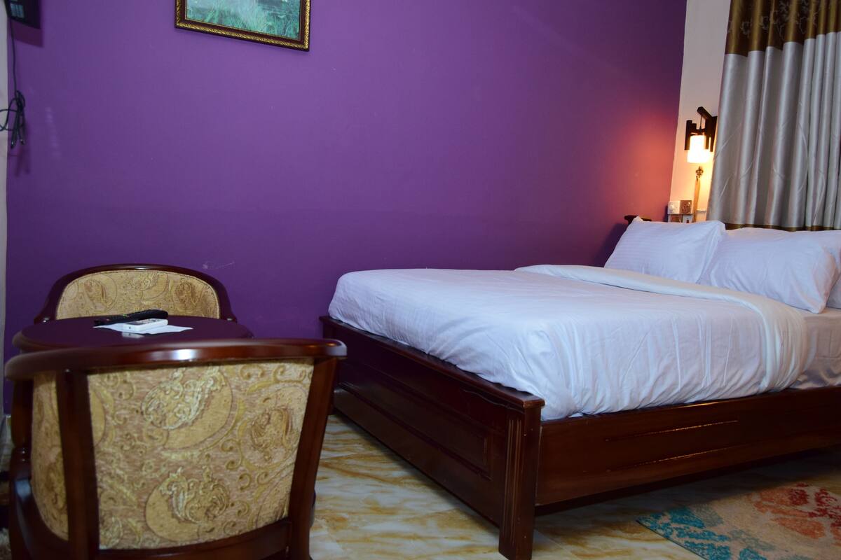 Une chambre d’hôtel avec un lit, une chaise et une table de chevet.