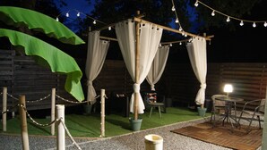 An outdoor patio area with a wooden pergola, string lights, and a seating arrangement. - Romantic room in nature (Lunas)