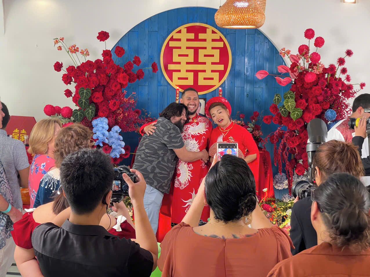 A group of people gathered around a stage with a traditional Chinese symbol backdrop, indicating a cultural or ceremonial event.