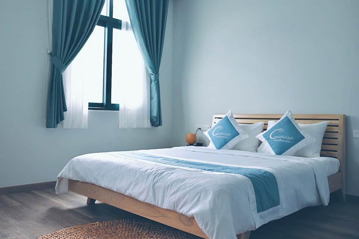 A bedroom with a bed, curtains, a bedside table, and a nightstand.