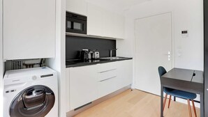 A compact kitchen with a washing machine, a microwave, and a coffee maker. - Studio Sleek & Refined - Levallois-Perret (Levallois-Perret)