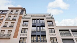 A multi-story building with a central entrance, large windows, and balconies. - Studio Sleek & Refined - Levallois-Perret (Levallois-Perret)