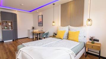 Cozy retreat with a neatly made bed, wooden bedside table, and a desk for work and relaxation.