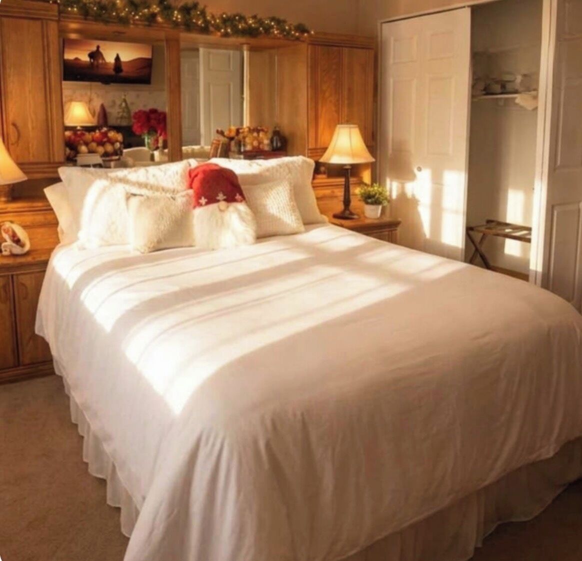 A neatly made bed with white bedding, a red pillow, and two bedside lamps.