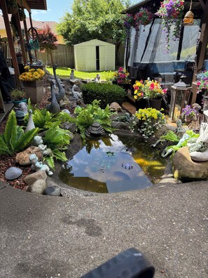 Un giardino con uno stagno, diverse piante e statue decorative.