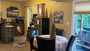 A dining area with a table set for four, surrounded by chairs. A small Christmas tree is on the table.