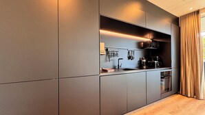 Une cuisine moderne avec des meubles de couleur grise, un plan de travail en bois et un four encastré.
