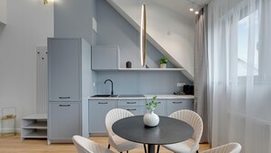 A modern kitchen with grey cabinets, a black countertop, and a white vase on the table.