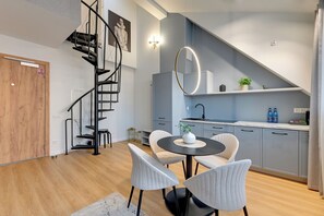 A modern kitchen with grey cabinets, a black spiral staircase, and a round mirror. - Waterlane Vintage Fitness & Gym by Downtown Apartments (Gdansk)