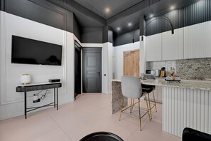 A modern kitchen with a marble countertop, a built-in oven, and a dining area with a bar stool. - Waterlane Vintage Fitness & Gym by Downtown Apartments (Gdansk)