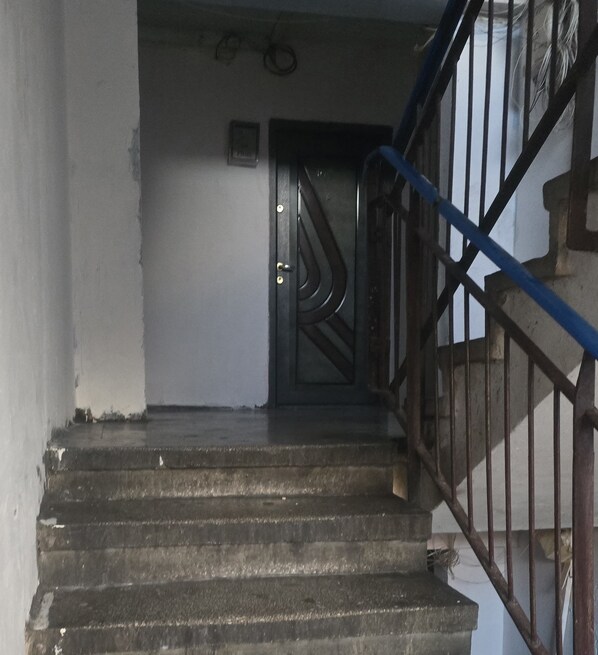 A staircase with a metal handrail and a door at the top. - Urban Studio for a Real Ghetto Experience (Craiova)