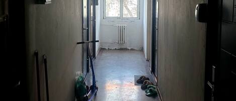 A narrow hallway with a radiator, a window, and a door on the right.