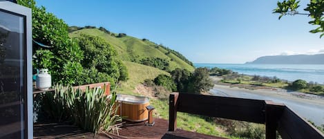 A wooden deck with a bench overlooking a coastal landscape.