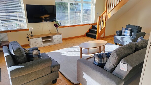 A modern living room with a grey sofa set, a coffee table, and a TV mounted on the wall. - Tranquil Retreat in Gorebridge (Gorebridge)