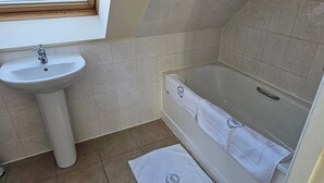 A bathroom with a white sink, a bathtub, and a window above the sink. - Tranquil Retreat in Gorebridge (Gorebridge)
