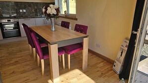 A dining area with a wooden table, purple upholstered chairs, and a vase with flowers. - Tranquil Retreat in Gorebridge (Gorebridge)
