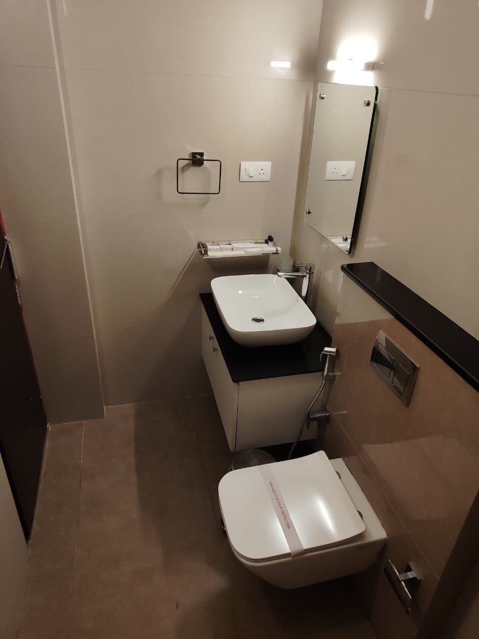 A compact bathroom with a white sink, a mirror, and a toilet.