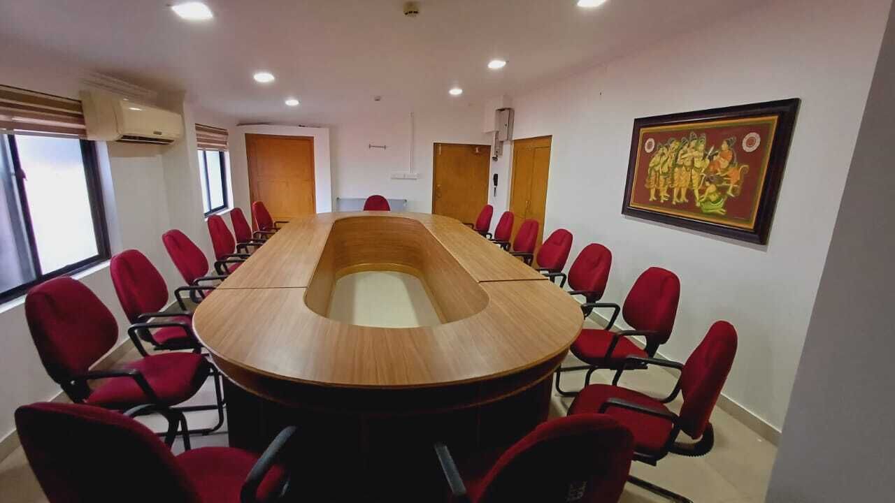 A conference room with a long table and red chairs, large windows, and a framed picture on the wall.