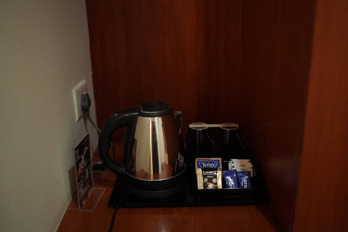 A coffee station with a kettle, cups, and coffee packets.