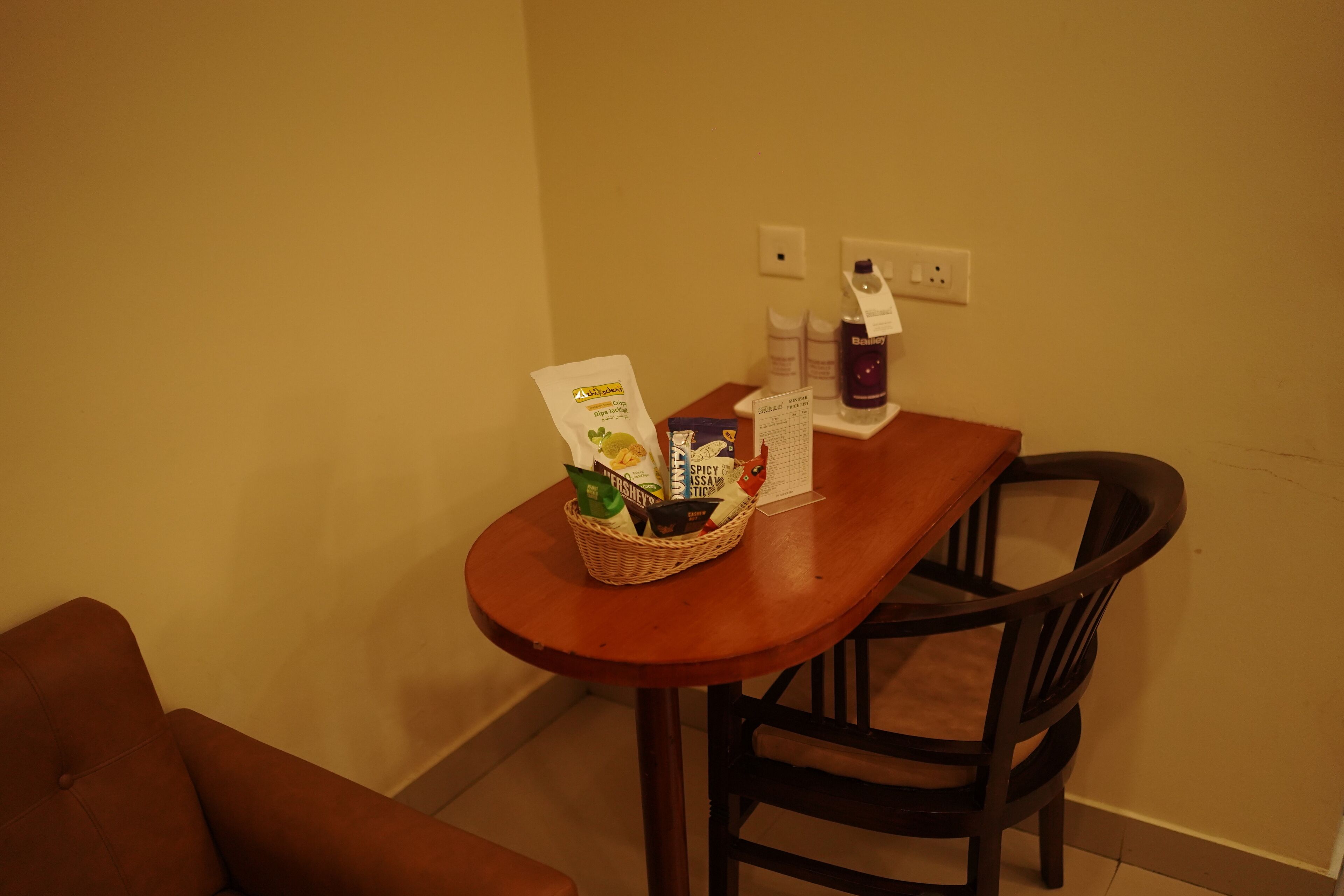Un comedor con una mesa de madera, una cesta de mimbre con alimentos, una botella de Baijiu y un menú.