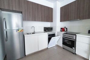 A compact kitchen with a refrigerator, microwave, stove, and dishwasher. - HAPPY SEASON I Park Heights 2 Dubai Hills 1BR  (Dubai)