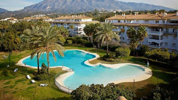 Un resort con una grande piscina, palme e una montagna sullo sfondo.