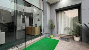 A modern interior with a reception desk, a staircase, and potted plants. - Bluo Stays - DLF Cybercity (Gurugram)