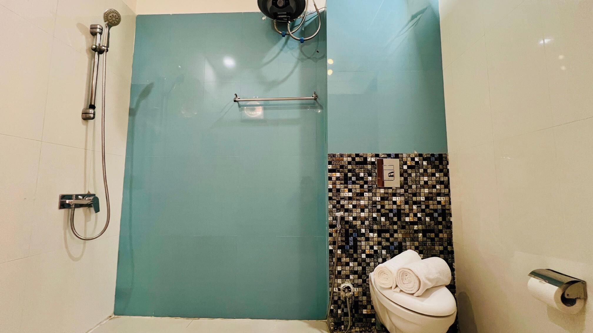 A bathroom with a shower, a toilet, and a towel rack.