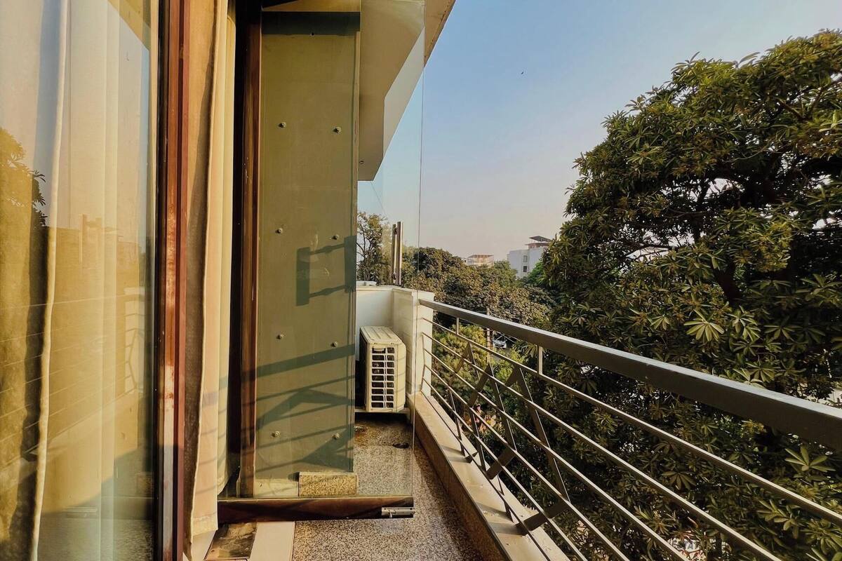 A balcony with a metal railing, a glass door, and a view of trees and buildings.
