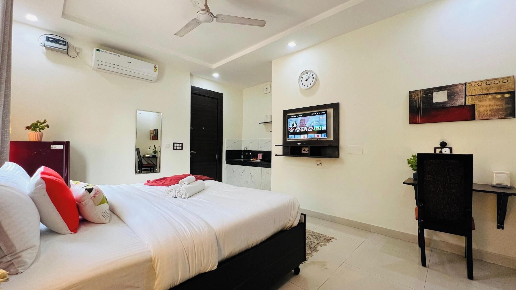 Una habitación de hotel moderna con una cama, un escritorio, un televisor y un ventilador de techo.