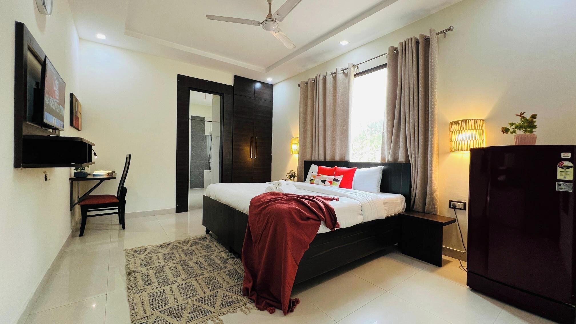 A modern bedroom with a bed, a desk, a chair, a wardrobe, and a ceiling fan.