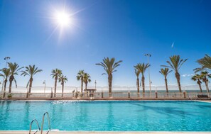 A swimming pool with a white fence, palm trees, and street lamps. - Cozy apartment in Málaga (Málaga)