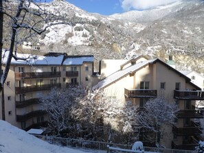 A snow-covered mountain town with multi-story buildings, balconies, and a clear sky.