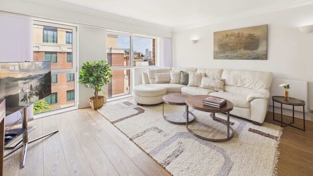 A modern living room with a sofa, coffee table, and a painting on the wall.