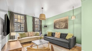 Un salon comprenant un canapé, un fauteuil, une table basse et un tableau accroché au mur.