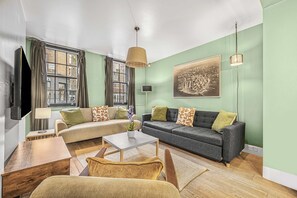 Ein Wohnzimmer mit Sofa, Sessel, Couchtisch und einem Bild an der Wand.