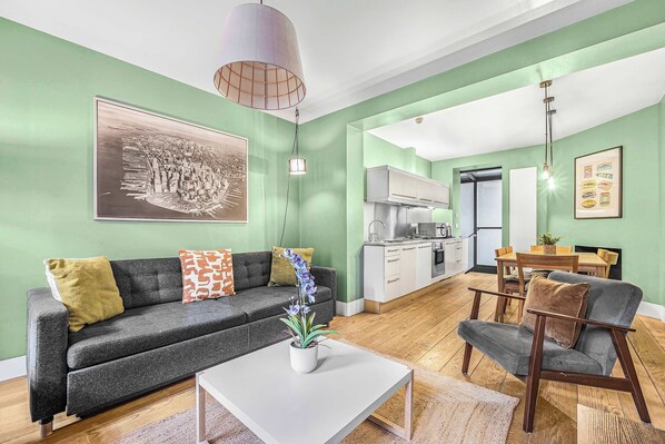 A modern living room with a sofa, coffee table, and a dining area with a table and chairs.