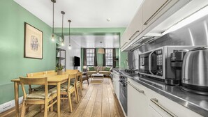 Une cuisine moderne avec un coin repas, un plancher en bois et un mur vert.