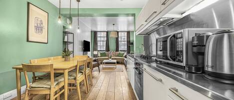 Une cuisine moderne avec un coin repas, un plancher en bois et un mur vert.