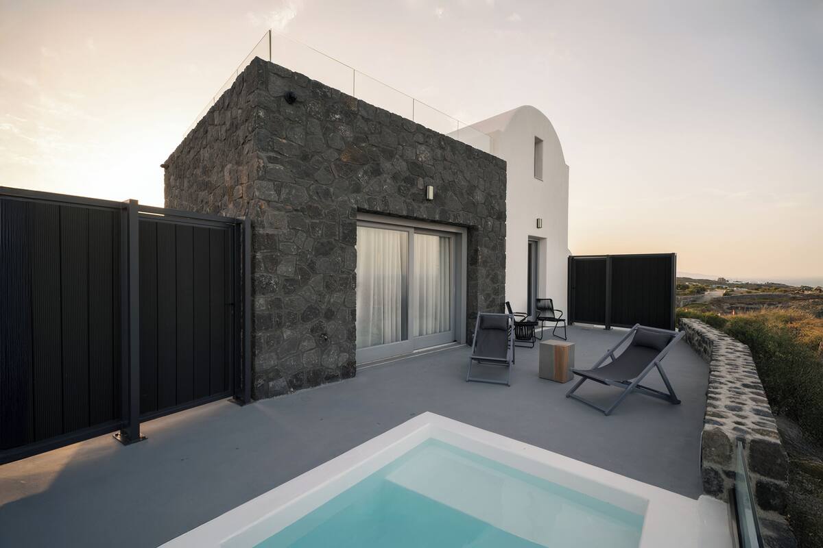 Una villa moderna con fachada de piedra, piscina y mobiliario de exterior.