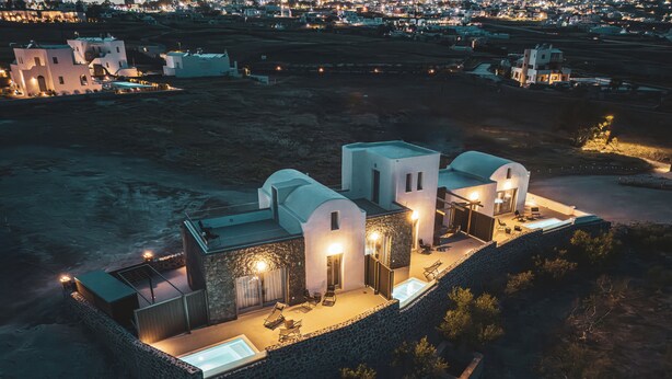 Una propiedad frente al mar con piscina, mobiliario de exterior y un muro de piedra.