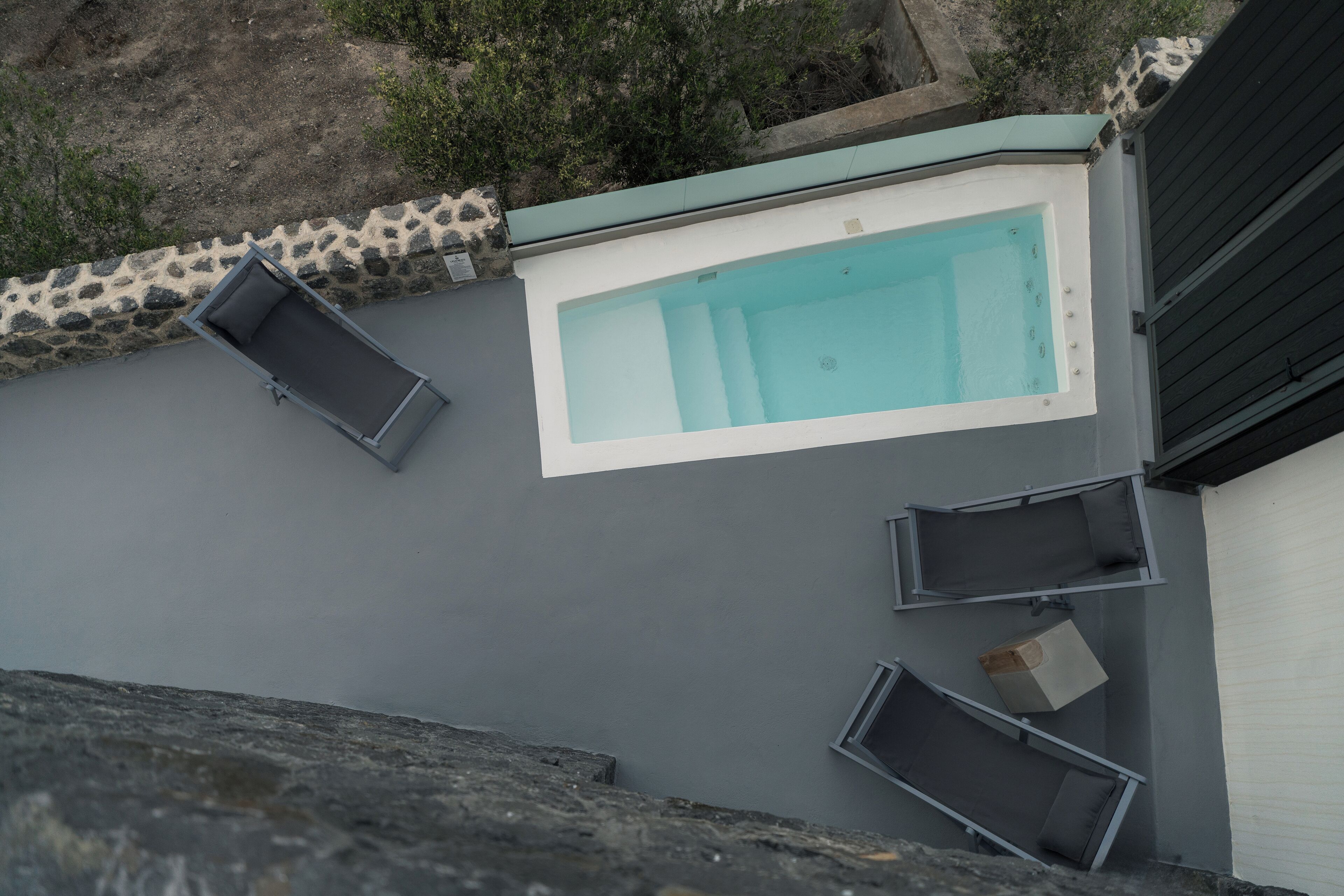 Una piscina en la azotea de forma rectangular, rodeada por un borde de piedra y una barandilla de metal.